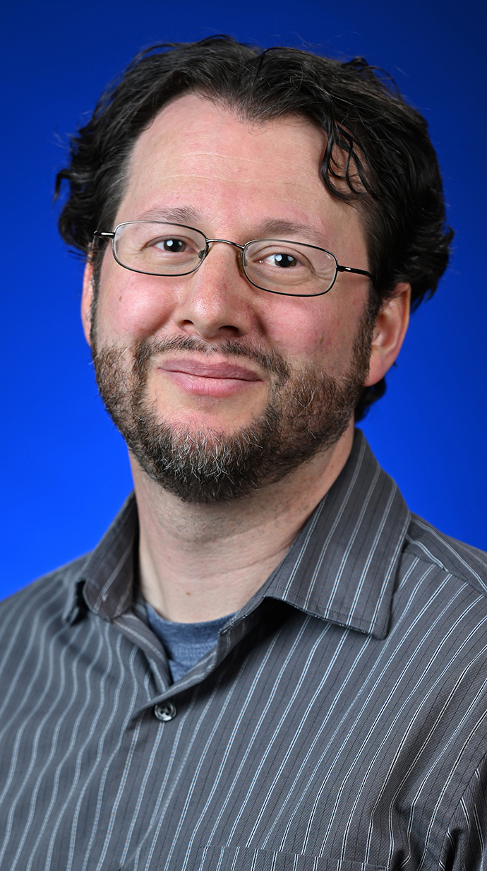 Headshot of a man wearing a gray shirt with a thin white stripe.