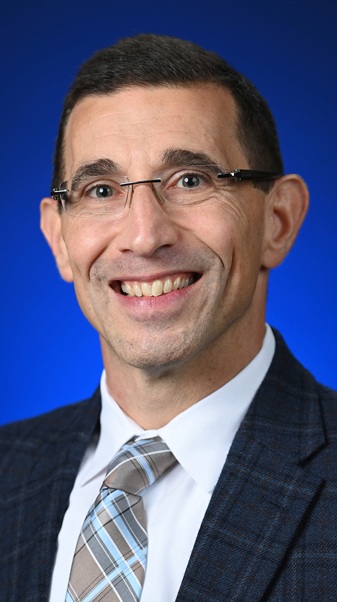 Headshot of a man wearing glasses and a dark suit.