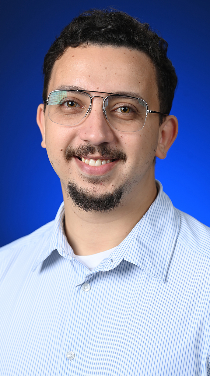Headshot of a man wearing glasses and a light blue dress shirt.