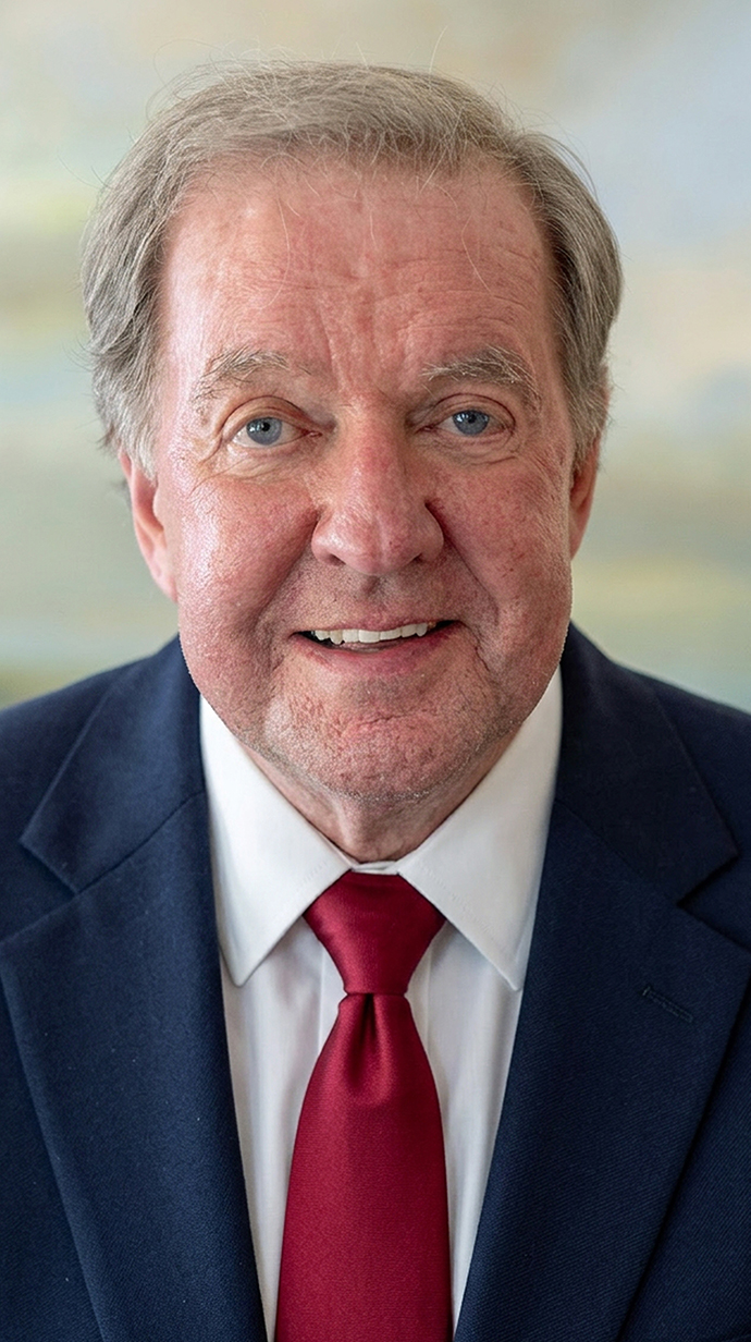Headshot of a man wearing a blue suit with a red tie.