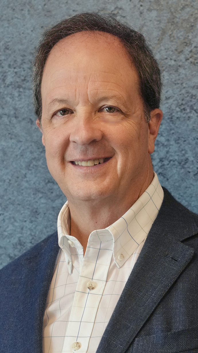 Headshot of a man wearing gray jacket over an open-collared dress shirt.