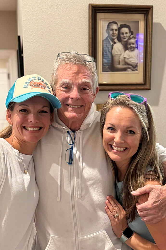 A man stands with his arms around two women in a home.
