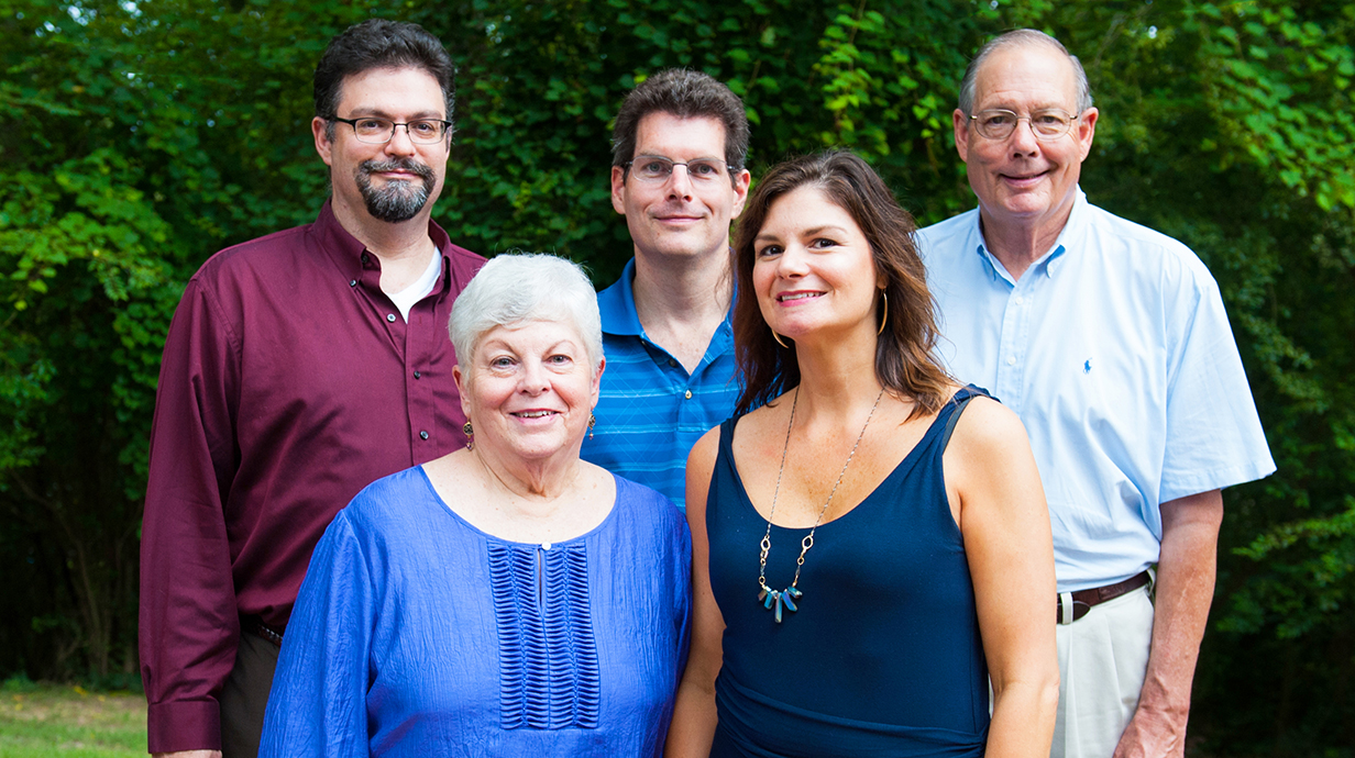 Three men and two women pose outdoors for a family photo.