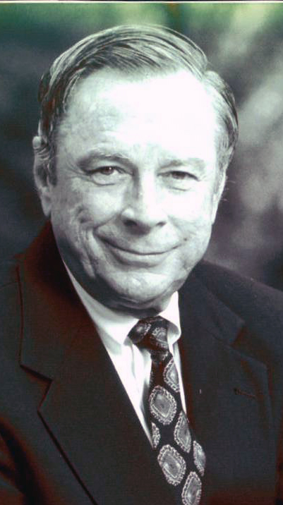Black-and-white headshot of a man wearing a dark suit.