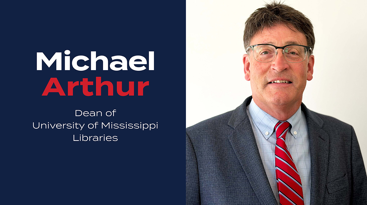 Headshot of a man wearing a blue suit with text overlaid to the left reading 'Michael Arthur: Dean of University of Mississippi Libraries.'