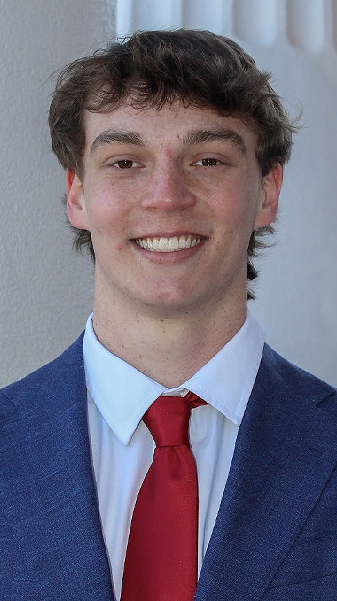 Headshot of a young man wearing a blue suit and a red tie.