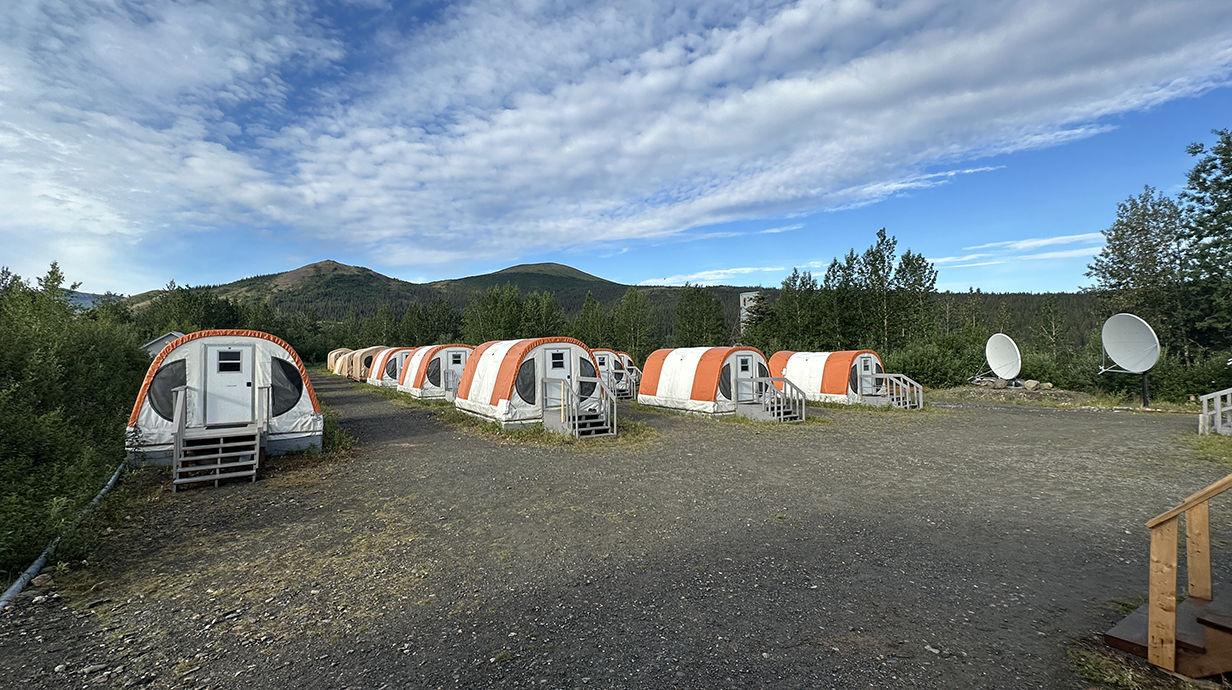 Rows of low tents sit on permanent foundations in a mountain valley.