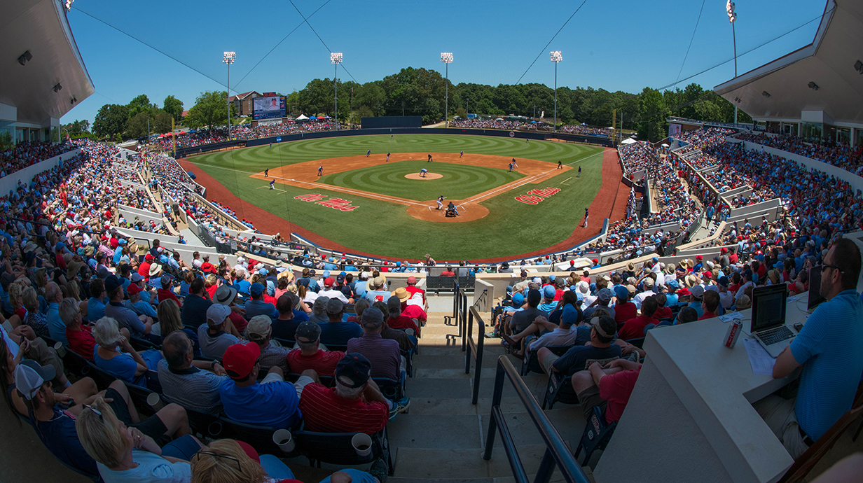A crowd fills a baseball stadium as a game progresses on the field.