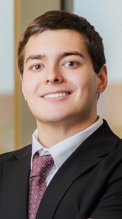 Headshot of a young man wearing a dark suit.