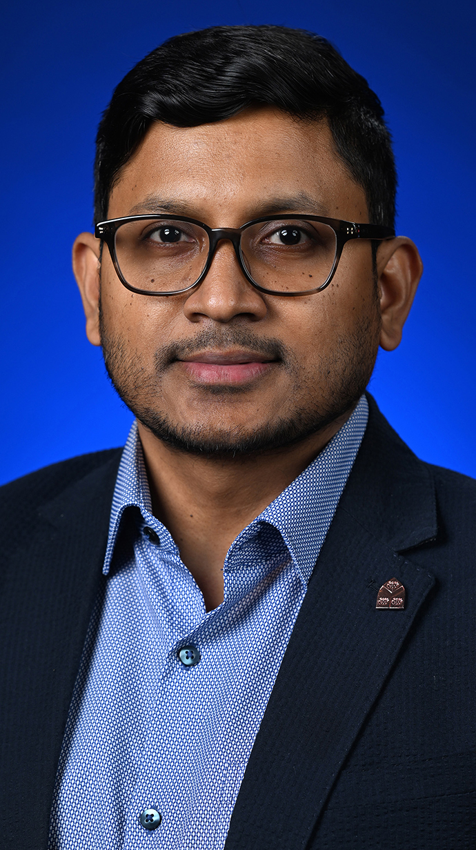 Headshot of a man wearing a dark blue jacket with a lighter blue shirt.