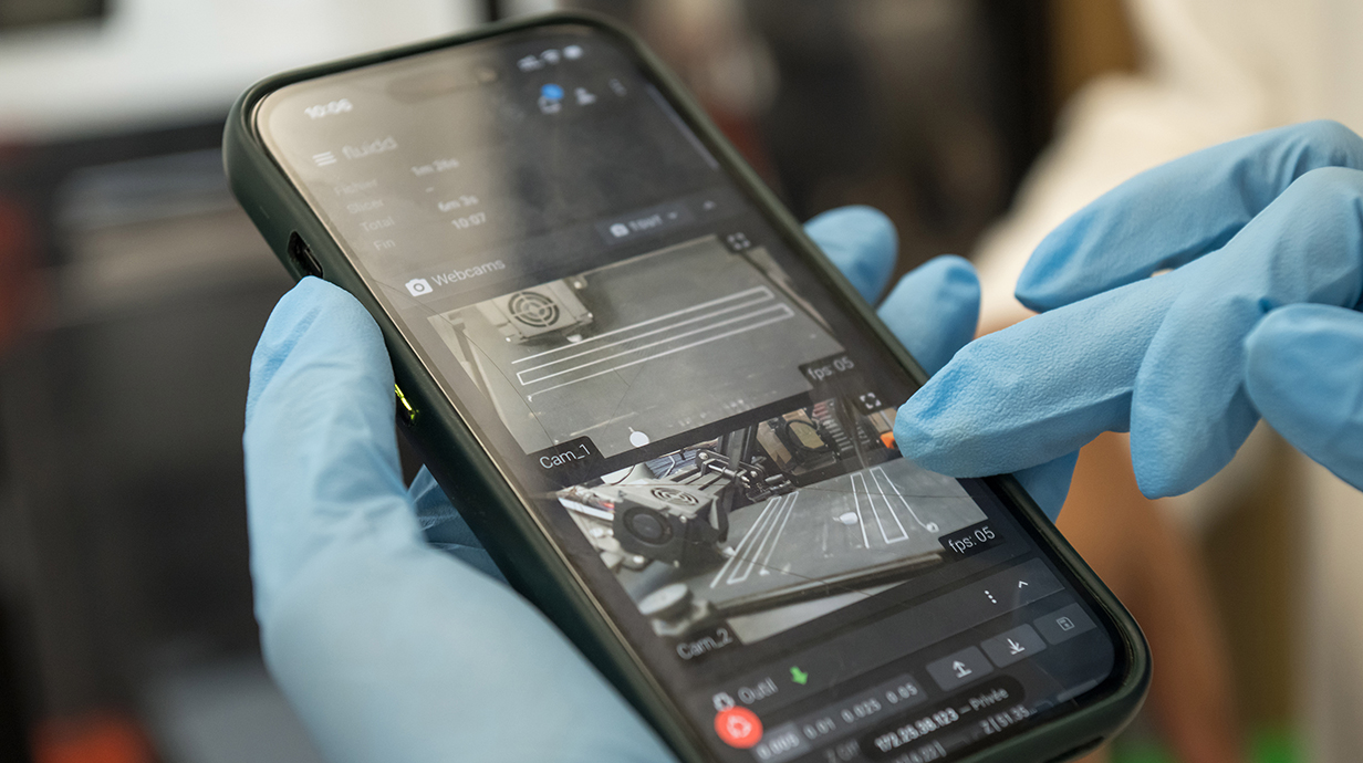 A person wearing blue rubber gloves uses a smartphone.