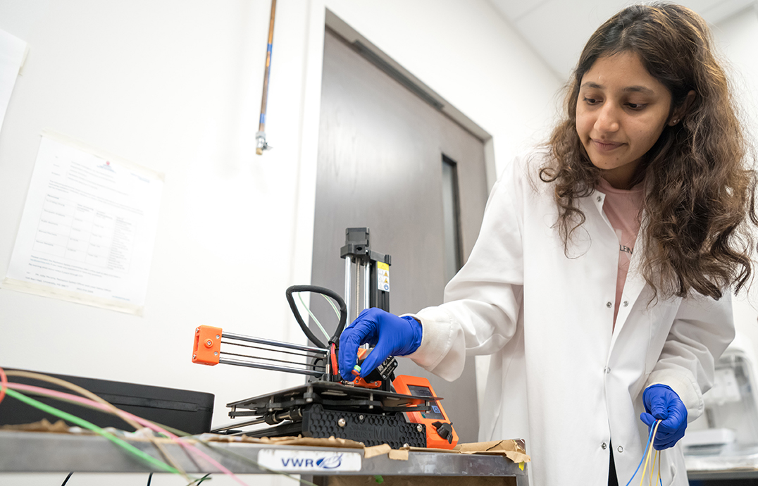 A woman works with a 3D printer in a lab.