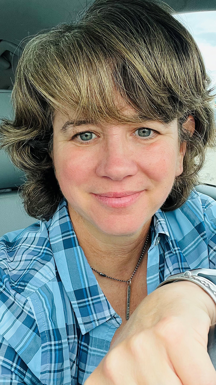 Headshot of a woman wearing a blue plaid shirt.