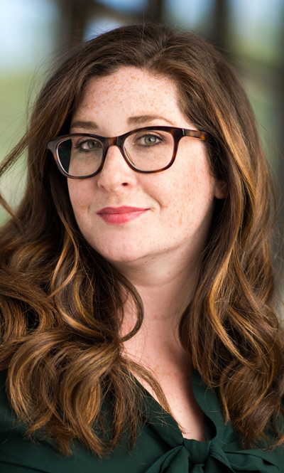 Headshot of a woman wearing glasses and a dark green blouse.