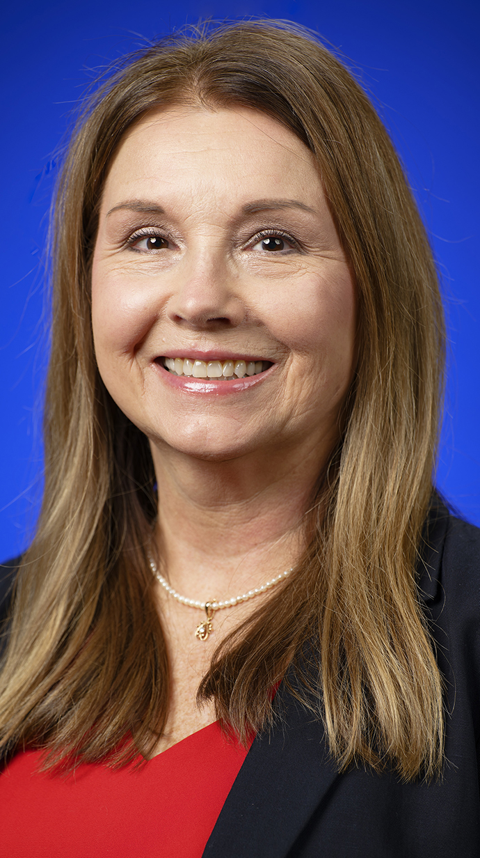 Headshot of a woman wearing a black jacket over a red blouse.