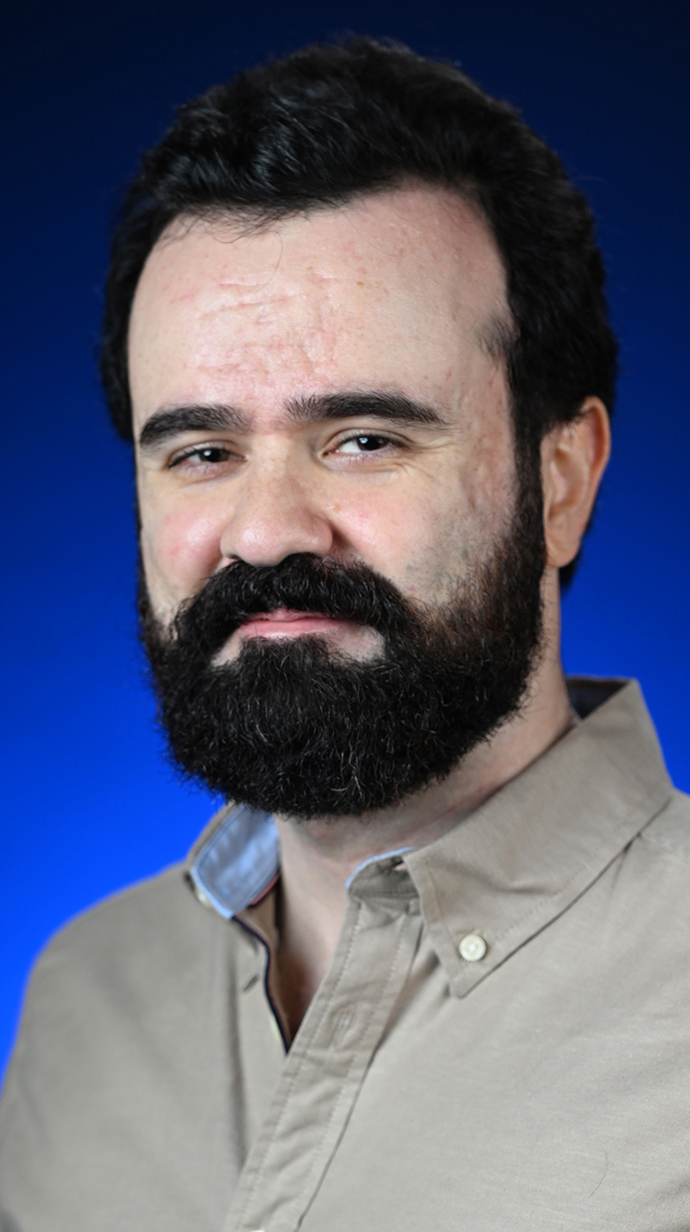 Headshot of a bearded man wearing a tan shirt.
