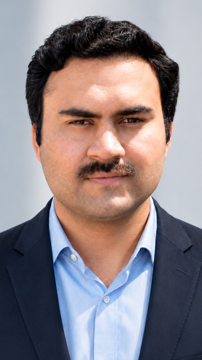 Headshot of a man wearing a dark blue jacket over a light blue dress shirt.