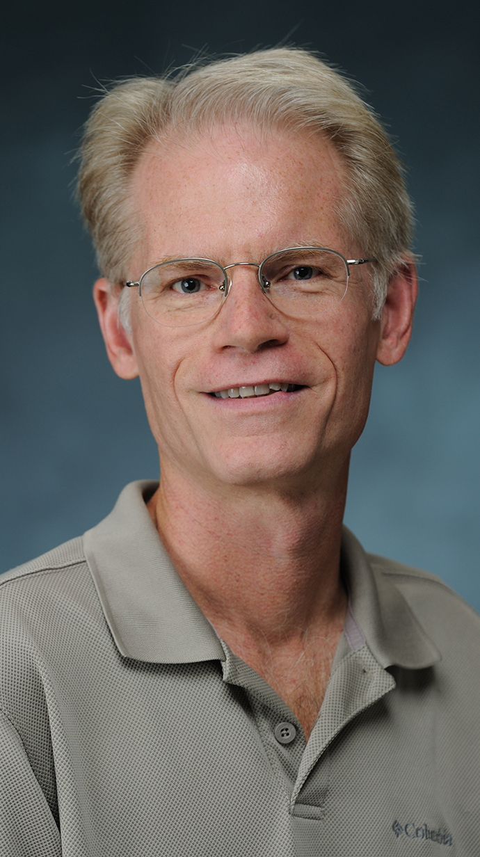 Headshot of a man wearing a tan polo shirt