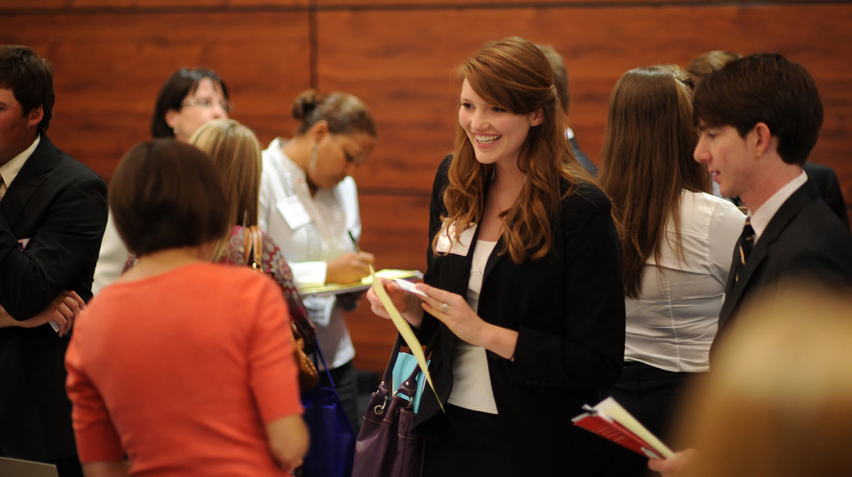 Student interacting with individuals at an event.