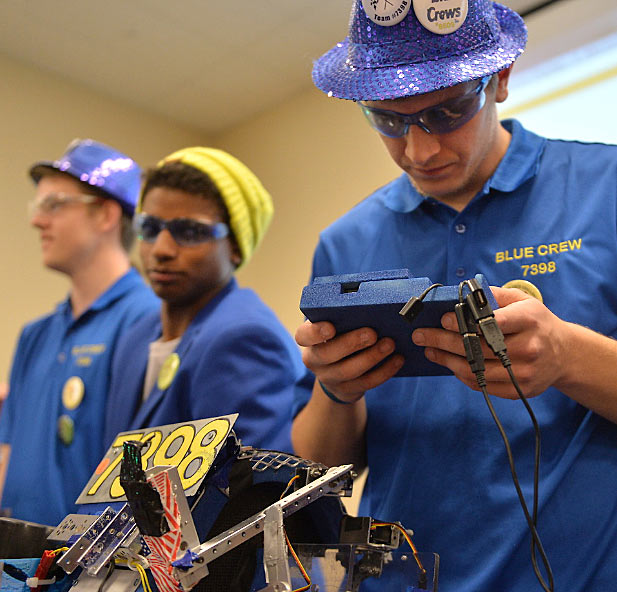 Students compete in robotics competition, holding video game controllers