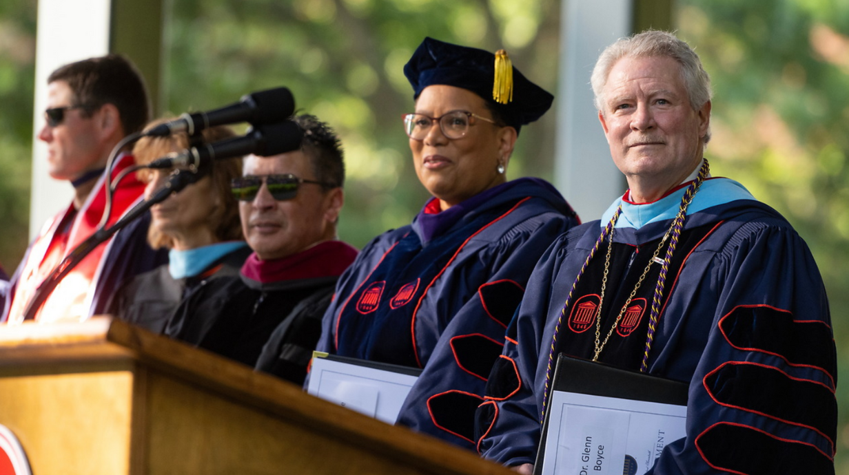 University leaders on stage prepare for a summer commencement.