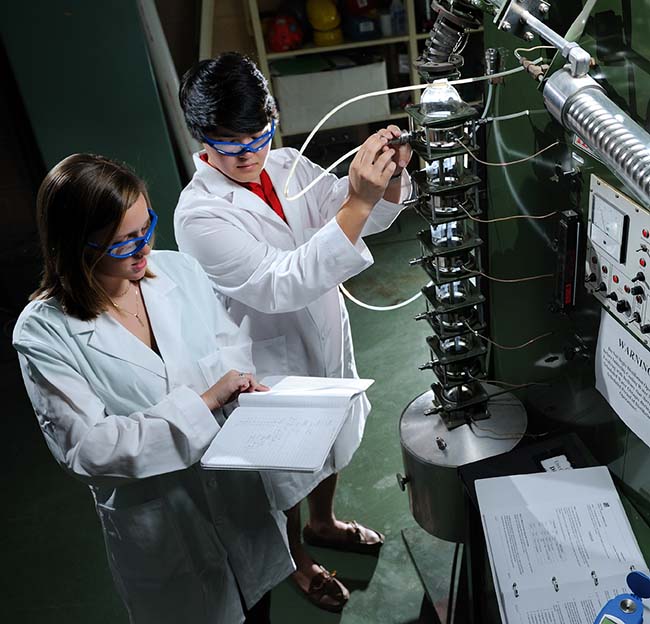 An Ole Miss chemical engineering student assists a professor with lab equipment.
