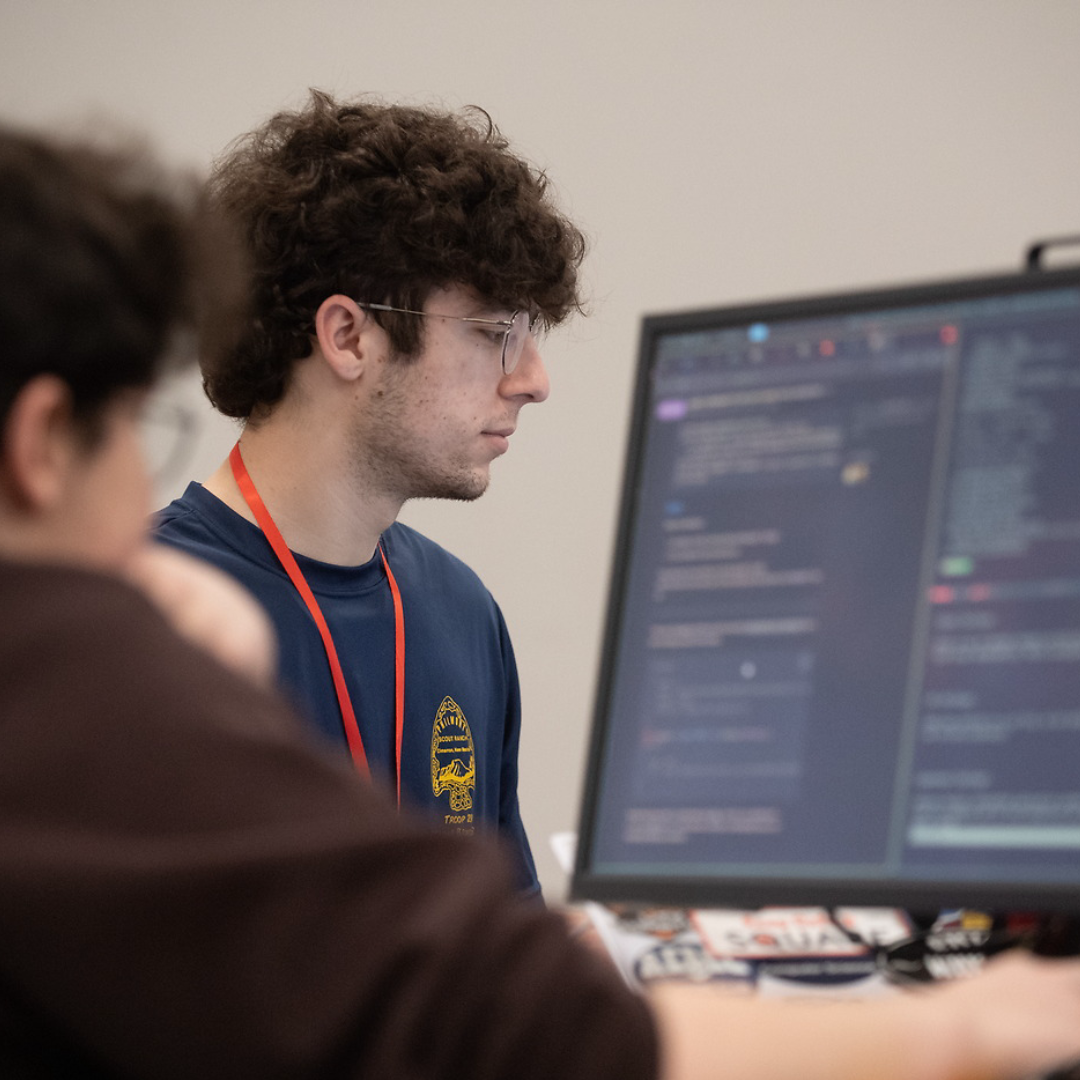 Student looking at a PC intently during the middle of a hackathon