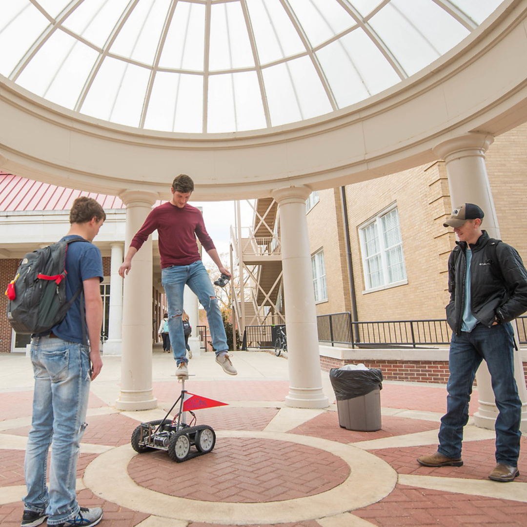 A mechanical engineering student load tests a robot by standing on top of it