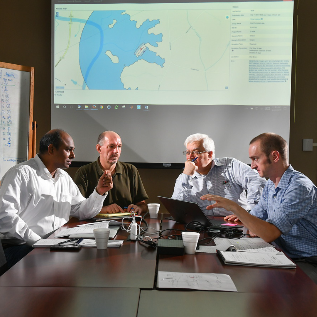 4 researchers for National Center for Computational Hydroscience and Engineering sit at a table discussing an issue