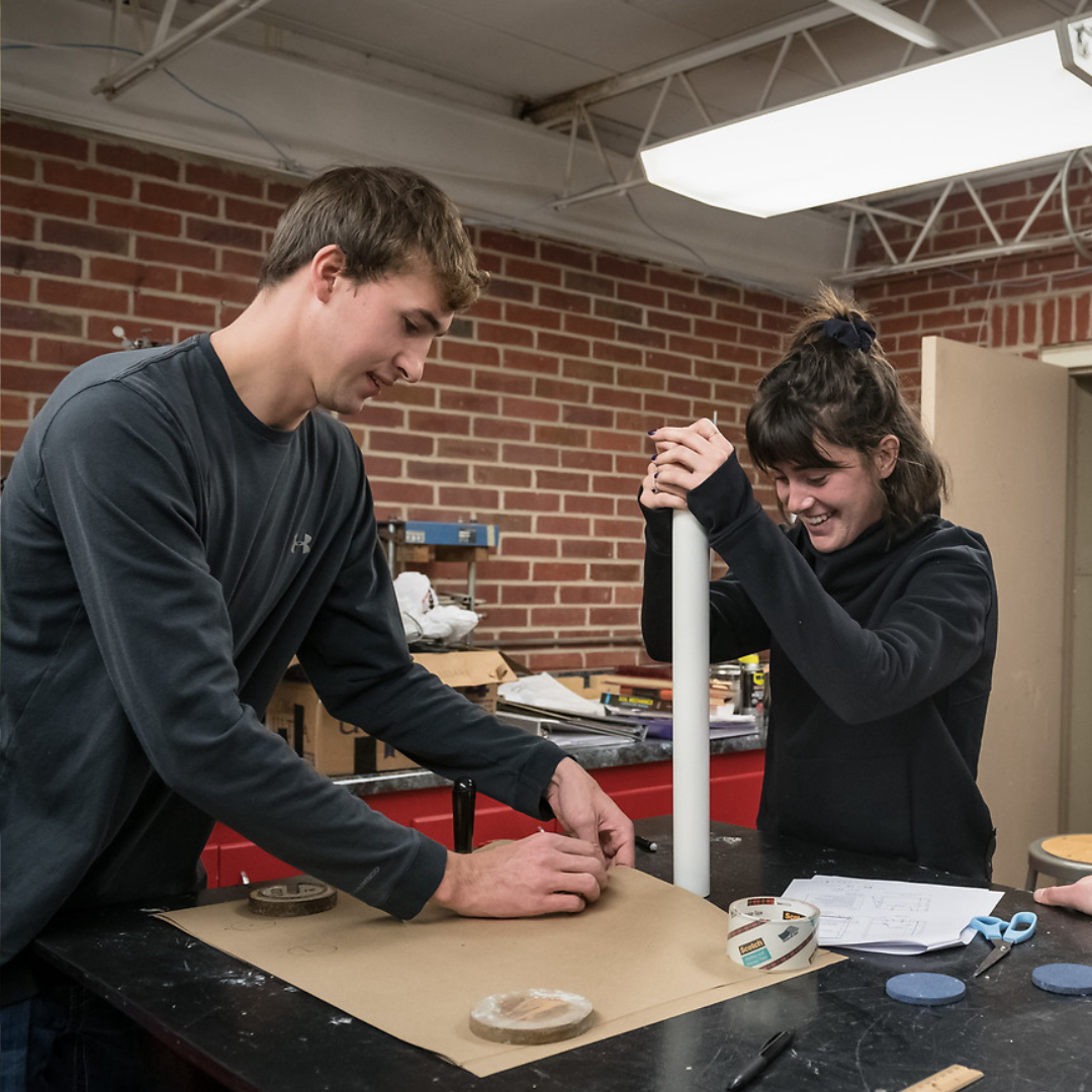 Two students work together to build a structure in a civil engineering lab