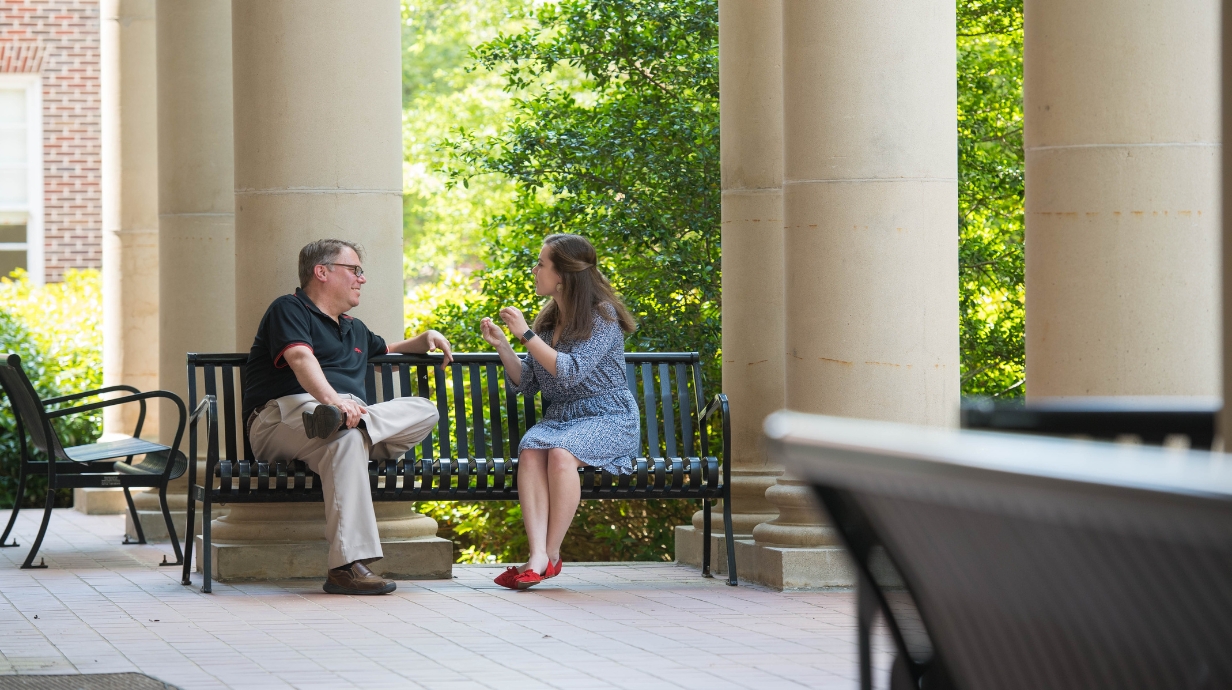 An instructor and student sitting on a bench talking