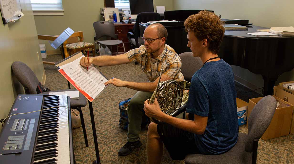 A French horn player receives one-on-one instruction from a member of the faculty.