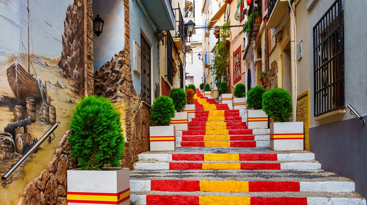 Narrow alley decorated with the flag of Spain on the steps.