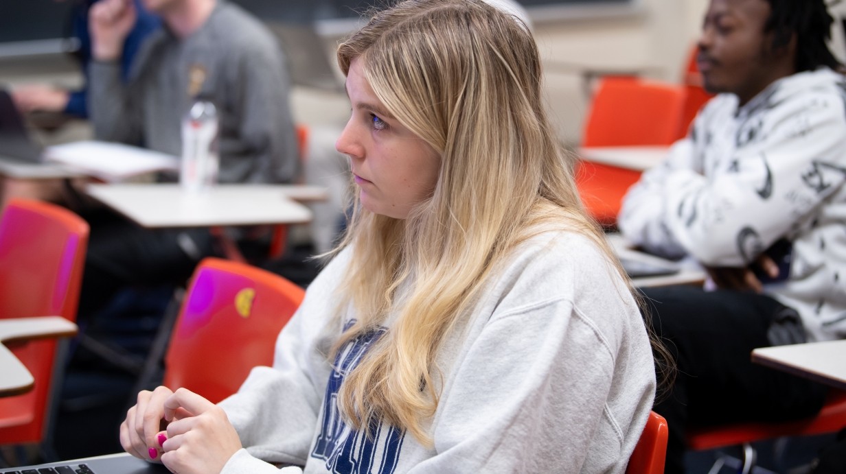 Student sitting in a classroom listening to a professor