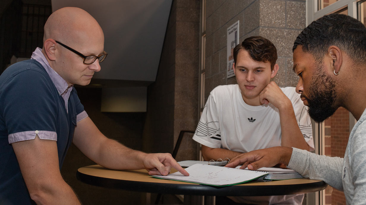 Professor and two students looking at a book