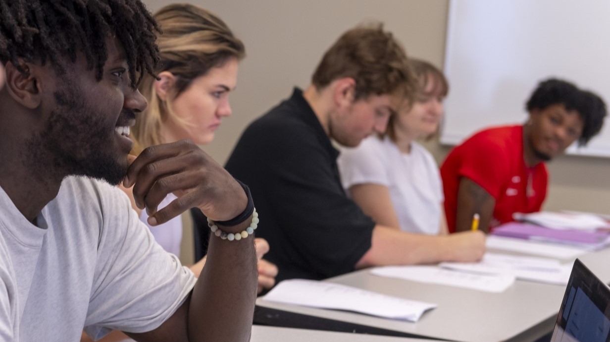 Students sitting in a line along the table in a class. 