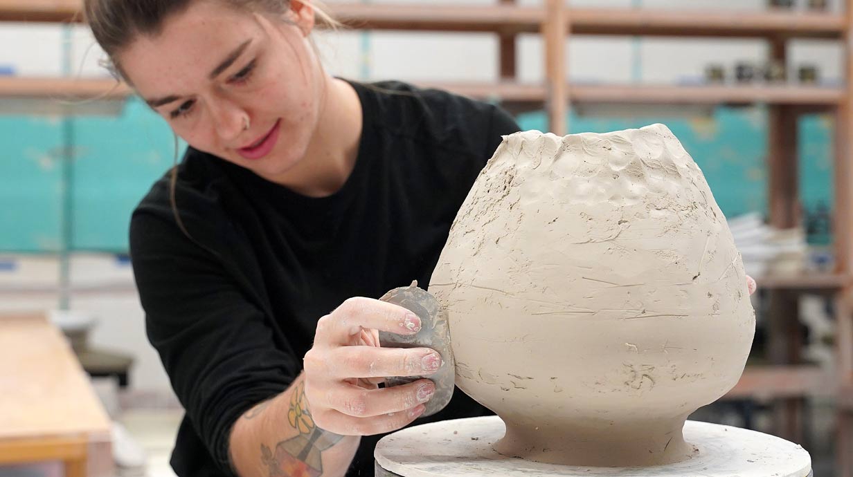 Student working on large ceramic vessel