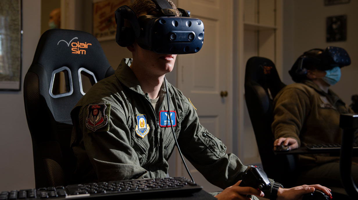 Student in uniform with virtual reality headset on sitting in flying simulator.