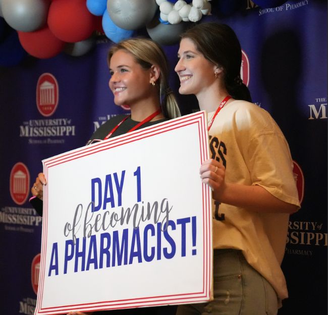 Two new admitted students holding 1st day of becoming a pharmacist sign