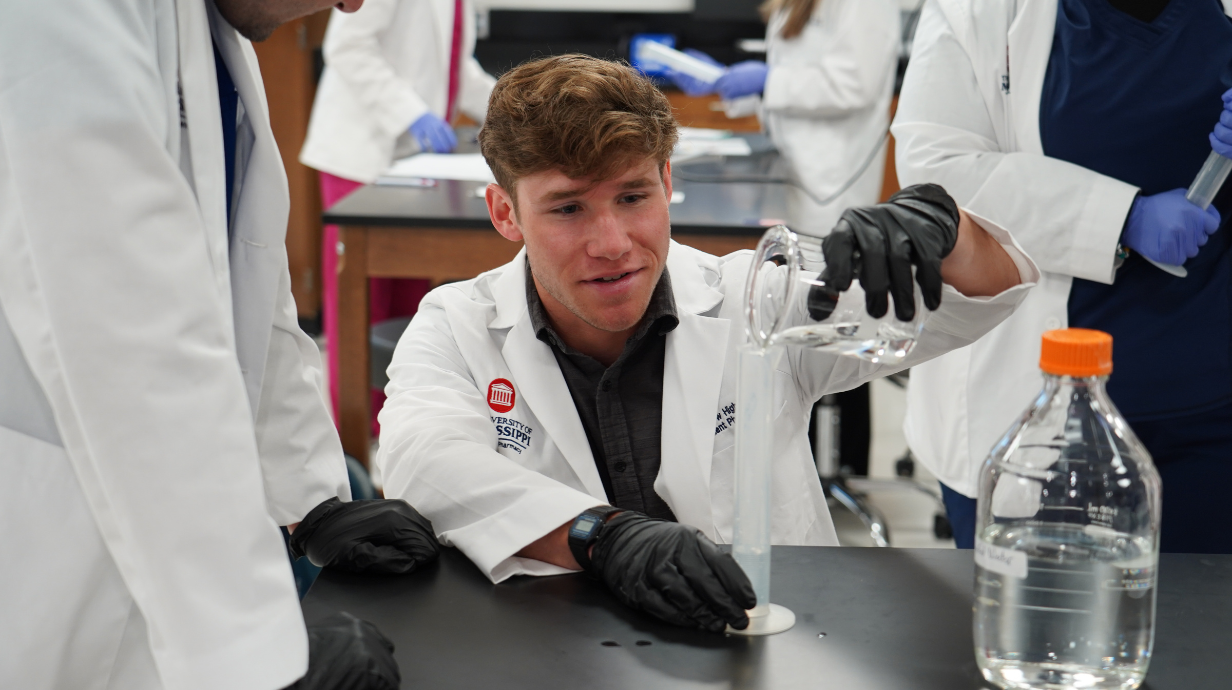 Ole Miss Pharmacy student pouring water into a beaker