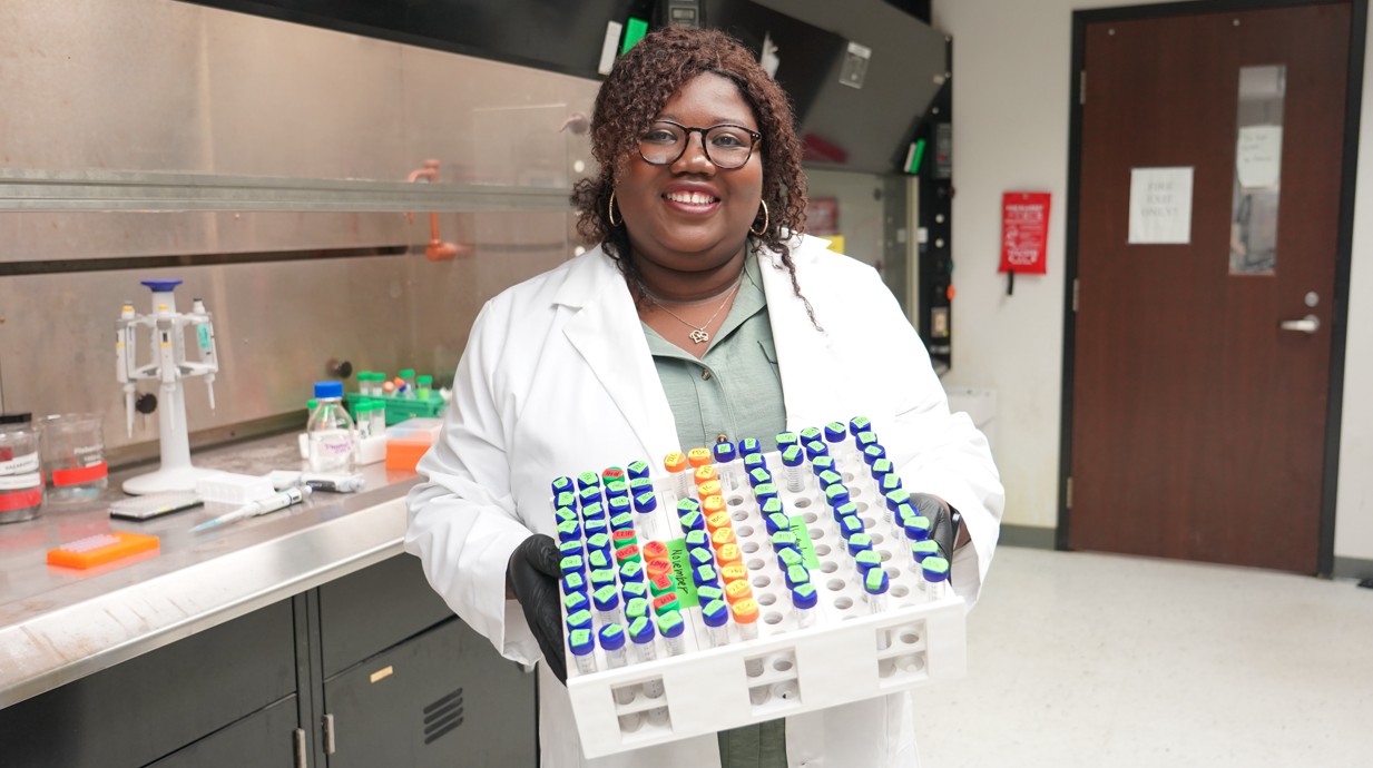 Photo of environmental toxicology student researcher studying a small fish under a microscope.