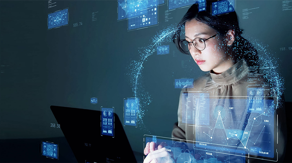 An image of a woman using a laptop, with holographic effects surrounding her.
