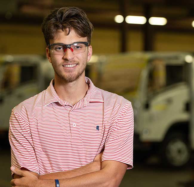 Junior Ole Miss mechanical engineering major Downing Koestler stands in front of heavy equipment during his internship at CITE Armored in Holly Springs. 