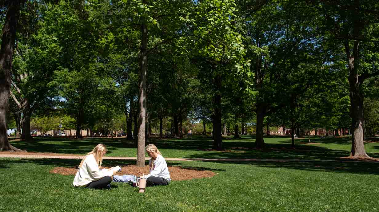 Two Ole Miss students enjoy a nice spring afternoon while studying in the Grove.