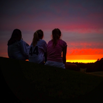 Three students relax and watch the sunset.