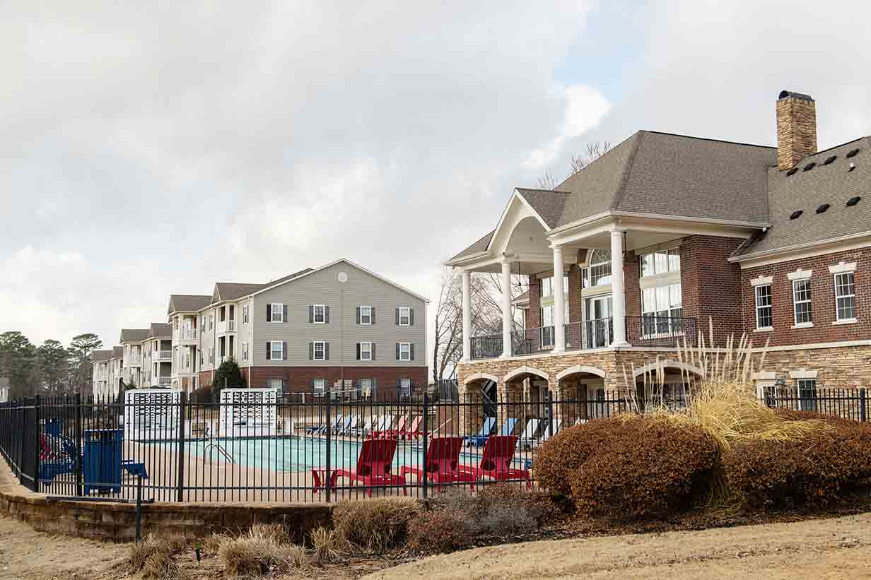 A view of the clubhouse and swimming pool with several apartment buildings in the background at The Quarters.