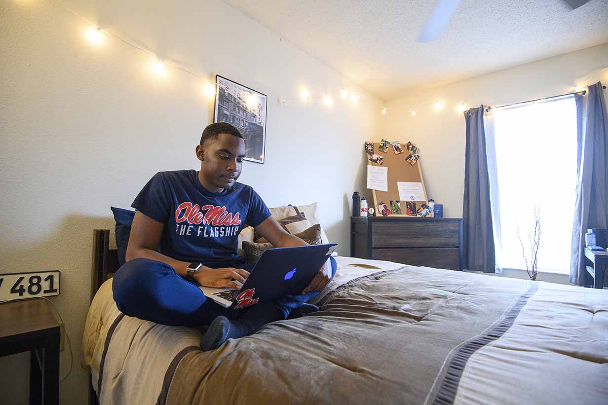 An Ole Miss student works on an assignment while relaxing in his apartment.