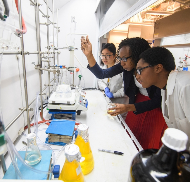 Three students in the lab with a faculty member.