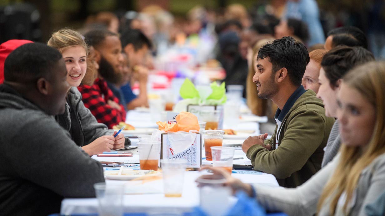 Ole Miss students are in the foreground with many more in the background, all eating together outside the Lyceum as part of the “Longest Table” event.