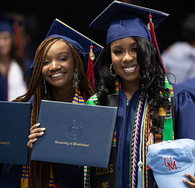 Two NPHC Sorority members pose with their diplomas during Ole Miss commencement